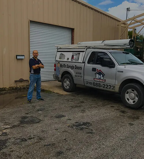 technician standing beside company truck in front of a garage door